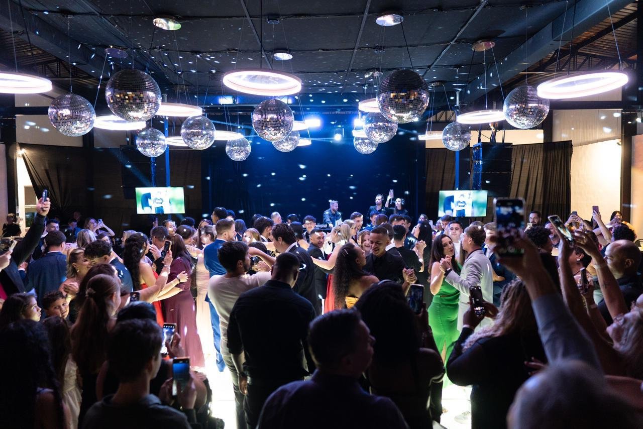 Pista de dança cheia sob globos espelhados na festa de formatura